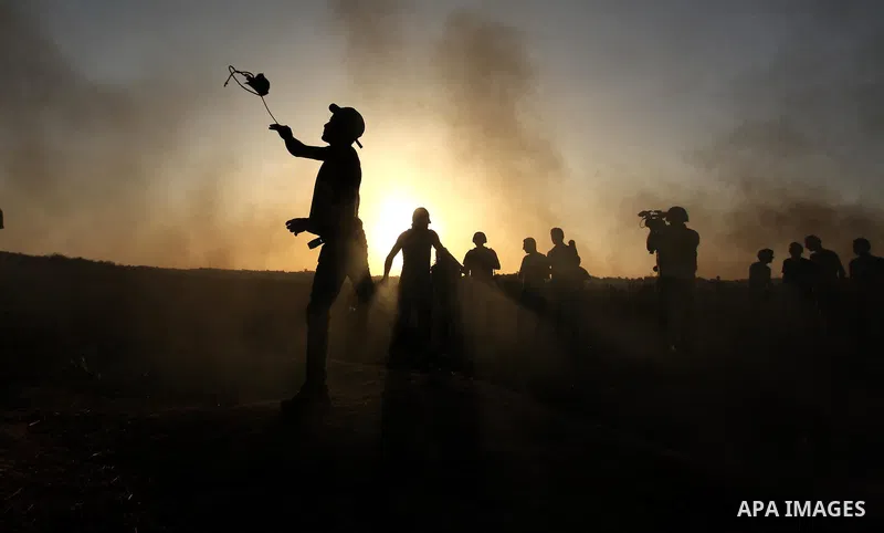 A masked Palestinian protester hurls a stone towards Israeli troops during clashes near a border fence between Israel and the Gaza Strip on October 14, 2015 east of Bureij in central Gaza. The outbreak of violence betwee...