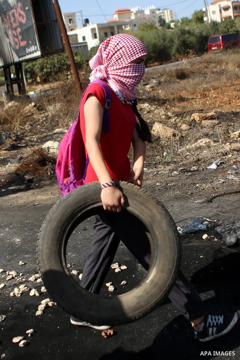 A female Palestinian protester burns tires during clashes with Israeli security forces near the Beit El settlement on the outskirts of Ramallah in the West Bank, on October 16, 2015. The unrest that has engulfed Jerusale...