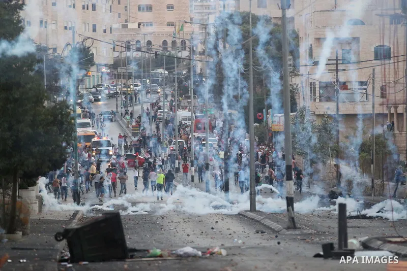 Palestinian protesters run for cover from tear gas during clashes with Israeli security forces at the main entrance of the West Bank city of Bethlehem on October 16, 2015. The unrest that has engulfed Jerusalem and the o...