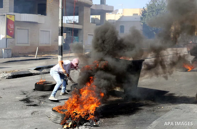A Palestinian protester burns tires during clashes with Israeli security forces at the main entrance of the West Bank city of Bethlehem on October 16, 2015. The unrest that has engulfed Jerusalem and the occupied West Ba...