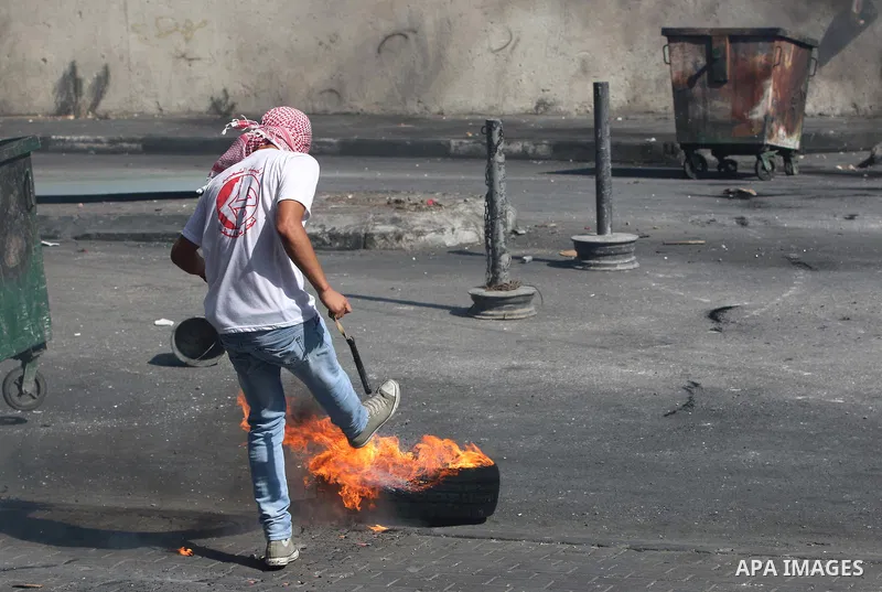 A Palestinian protester kicks a burning tire towards Israeli security forces during clashes at the main entrance of the West Bank city of Bethlehem on October 16, 2015. The unrest that has engulfed Jerusalem and the occu...