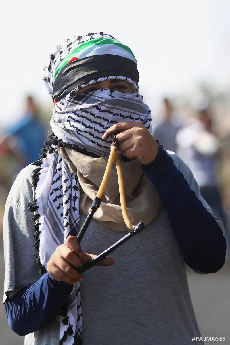 A female Palestinian protester uses a sling shot to throw stones at Israeli security forces during clashes with Israeli security forces near the Beit El settlement on the outskirts of Ramallah in the West Bank, on Octobe...