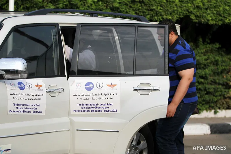 International Observers arrive at the entrance of a polling center, before polls open, during the first round of the parliamentary election in Cairo, Egypt, Sunday, Oct. 18, 2015. Photo by Amr Sayed