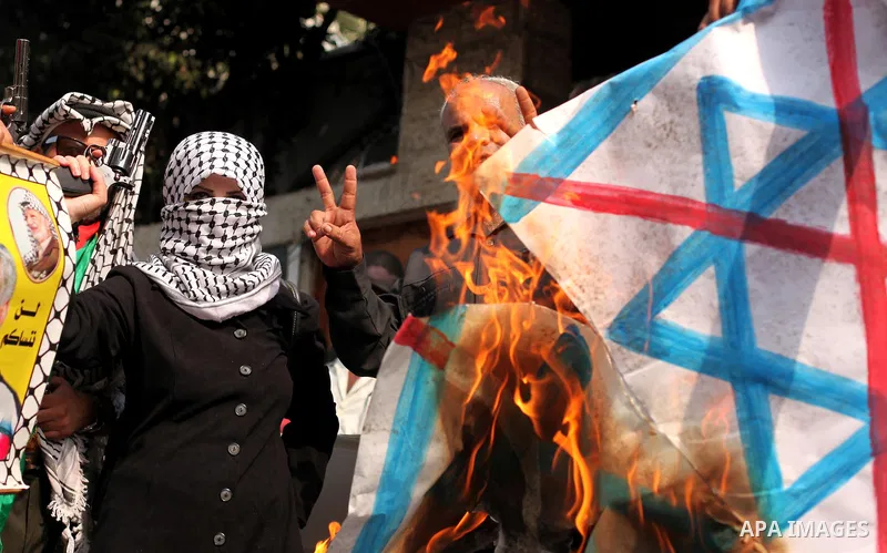 A Palestinian woman burns an Israeli flag during in an anti-Israel protest in front of Red cross office, in Gaza city, on Oct. 19, 2015. Israel pressed ahead with major security measures after five more stabbing incident...