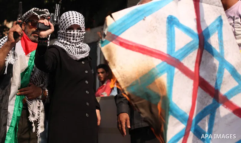A Palestinian woman burns an Israeli flag during in an anti-Israel protest in front of Red cross office, in Gaza city, on Oct. 19, 2015. Israel pressed ahead with major security measures after five more stabbing incident...