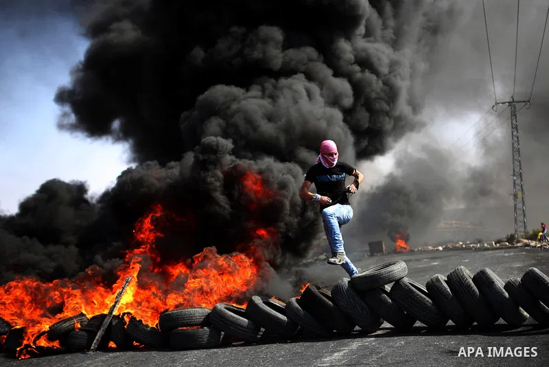 A Palestinian protester burns tires during clashes with Israeli security forces near the Jewish settlement of Beit El, near the West Bank city of Ramallah October 20, 2015. Triggered by Israeli incursions into the Al-Aqs...