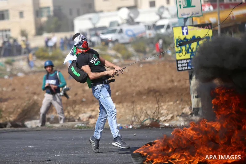 A Palestinian protester uses a sling shot to throw stones during clashes with Israeli security forces near the Jewish settlement of Beit El, near the West Bank city of Ramallah October 20, 2015. Triggered by Israeli incu...