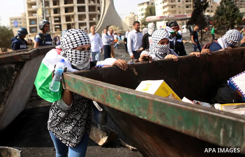 Palestinian protesters push a trash container during clashes with Israeli security forces near the Jewish settlement of Beit El, near the West Bank city of Ramallah October 20, 2015. Triggered by Israeli incursions into...