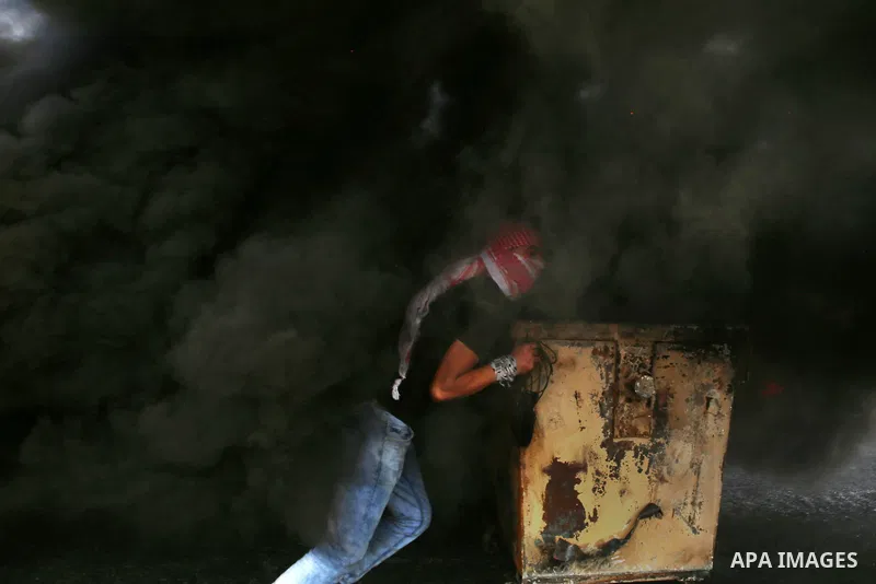 A Palestinian protester pushes a trash container during clashes with Israeli security forces near the Jewish settlement of Beit El, near the West Bank city of Ramallah October 20, 2015. Triggered by Israeli incursions in...