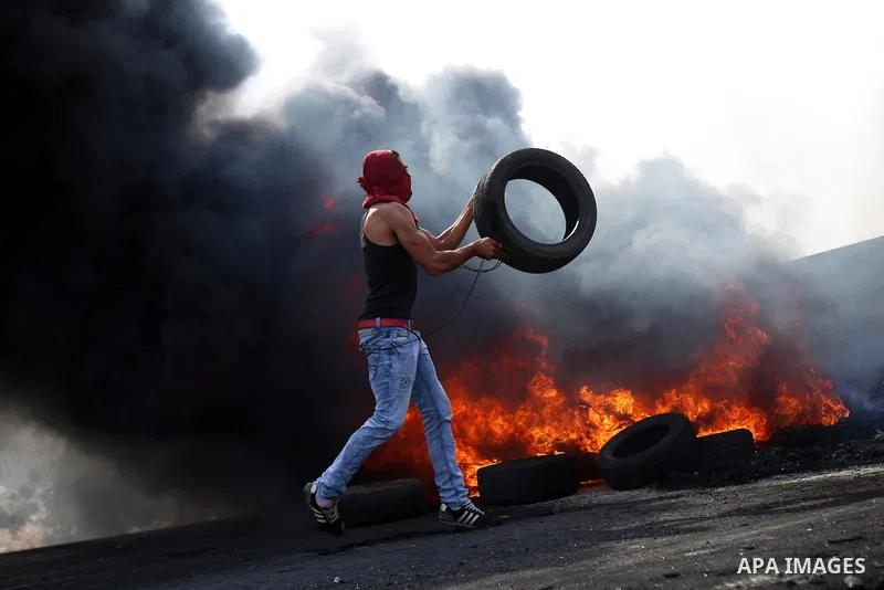 A Palestinian protester burns tires during clashes with Israeli security forces near the Jewish settlement of Beit El, near the West Bank city of Ramallah October 20, 2015. Triggered by Israeli incursions into the Al-Aqs...