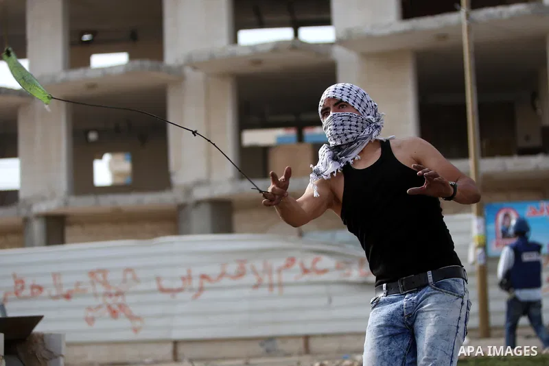 A Palestinian protester uses a sling shot to throw stones during clashes with Israeli security forces near the Jewish settlement of Beit El, near the West Bank city of Ramallah October 20, 2015. Triggered by Israeli incu...