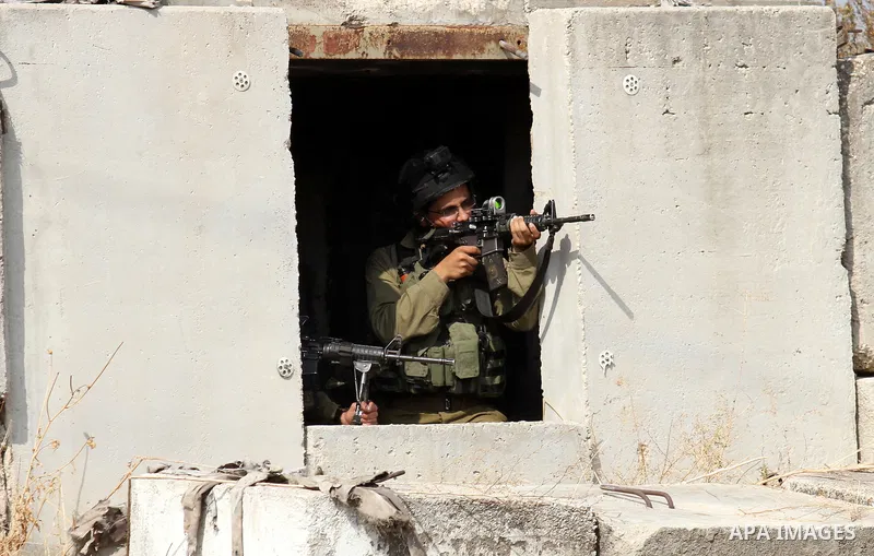 An Israeli soldier aims at Palestinian protesters during clashes in the West Bank town of Tulkarm, October 20, 2015. Triggered by Israeli incursions into the Al-Aqsa Mosque compound last month, violence and protests agai...