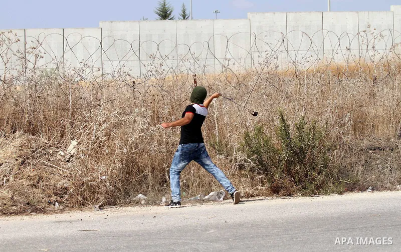 A Palestinian protester uses a sling shot to throw stones at Israeli security forces during clashes in the West Bank town of Tulkarm, October 20, 2015. Triggered by Israeli incursions into the Al-Aqsa Mosque compound las...