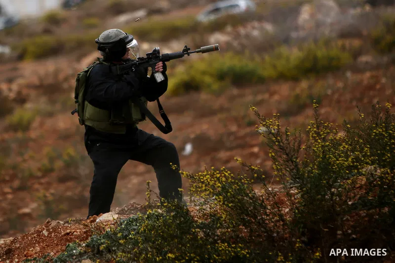 An Israeli border police fires towards Palestinian protesters during clashes near the Jewish settlement of Beit El, near Ramallah on October 23, 2015. Palestinian factions called for mass rallies against Israel in the oc...