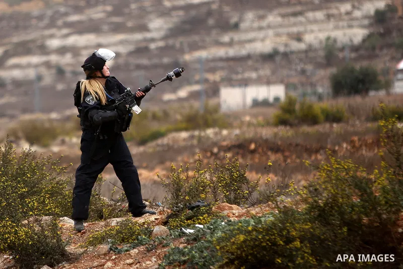 A female Israeli border police fires tear gas towards Palestinian protesters during clashes near the Jewish settlement of Beit El, near Ramallah on October 23, 2015. Palestinian factions called for mass rallies against I...