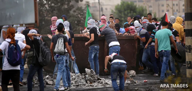 Palestinian protesters take cover during clashes with Israeli security forces near the Jewish settlement of Beit El, near Ramallah on October 23, 2015. Palestinian factions called for mass rallies against Israel in the o...