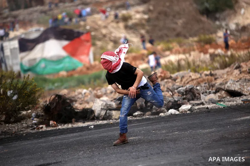 A Palestinian protester uses a sling shot to throw stones during clashes with Israeli security forces near the Jewish settlement of Beit El, near Ramallah on October 23, 2015. Palestinian factions called for mass rallies...