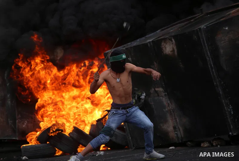 A Palestinian protester uses a sling shot to throw stones during clashes with Israeli security forces near the Jewish settlement of Beit El, near Ramallah on October 23, 2015. Palestinian factions called for mass rallies...