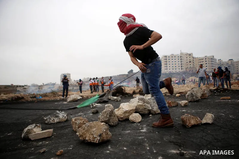 A Palestinian protester uses a sling shot to throw stones during clashes with Israeli security forces near the Jewish settlement of Beit El, near Ramallah on October 23, 2015. Palestinian factions called for mass rallies...