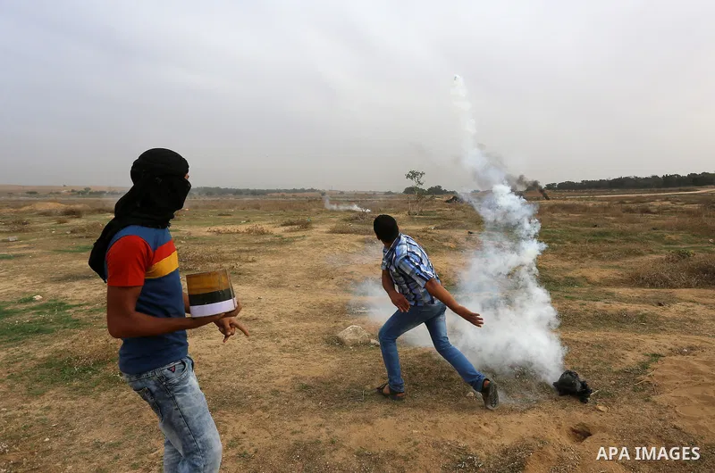 A Palestinian protester throws back a tear gas canister during clashes with Israeli security forces near the border between Israeli and central Gaza Stirp, on October 23, 2015. Palestinian factions called for mass rallie...