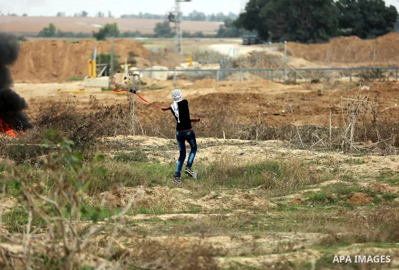 A Palestinian protester uses a sling shot to throw stones during clashes with Israeli security forces near the border between Israeli and central Gaza Strip, on October 23, 2015. Palestinian factions called for mass rall...