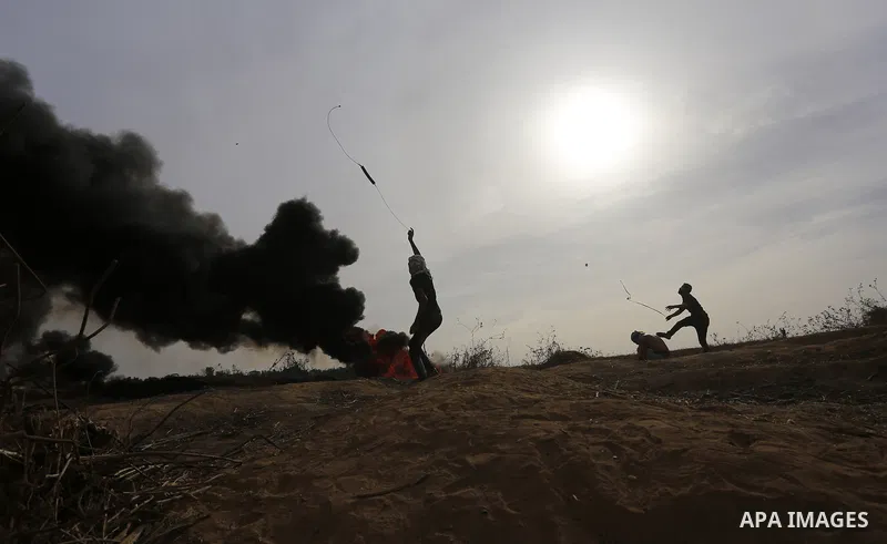 A Palestinian protester uses a sling shot to throw stones during clashes with Israeli security forces near the border between Israeli and central Gaza Strip, on October 23, 2015. Palestinian factions called for mass rall...