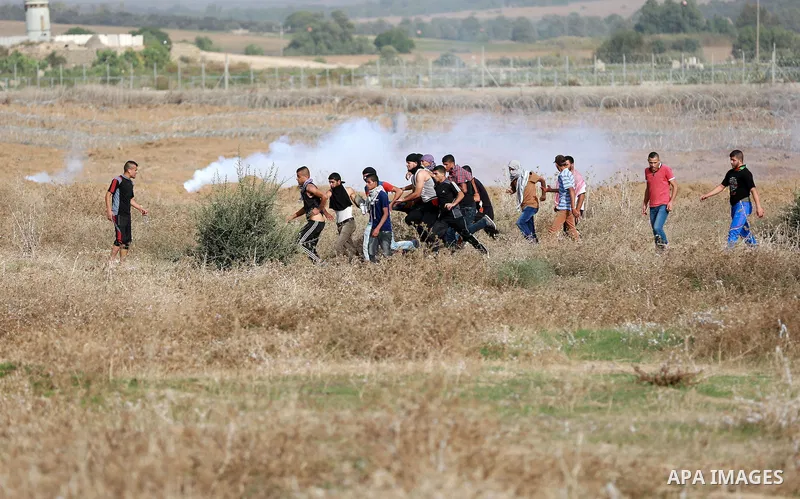 Palestinian protesters carry an injured comrade during clashes with Israeli security forces near the border between Israeli and central Gaza Strip, on October 23, 2015. Palestinian factions called for mass rallies agains...