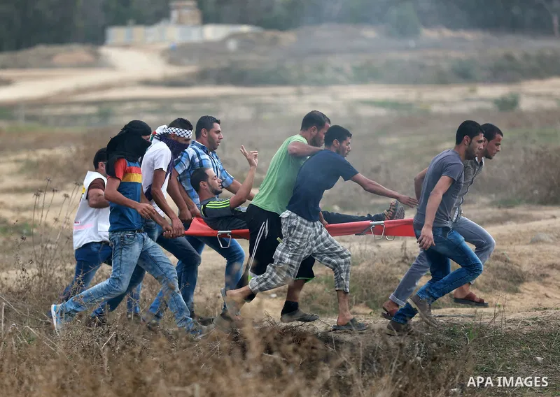Palestinian protesters carry an injured comrade during clashes with Israeli security forces near the border between Israeli and central Gaza Strip, on October 23, 2015. Palestinian factions called for mass rallies agains...