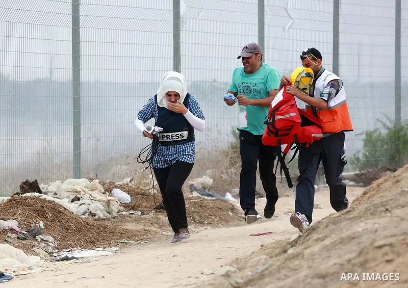 Palestinian journalists run for cover as they suffer from tear gas fired by Israeli security forces during clashes with Palestinian protesters near the border between Israeli and central Gaza Strip, on October 23, 2015....