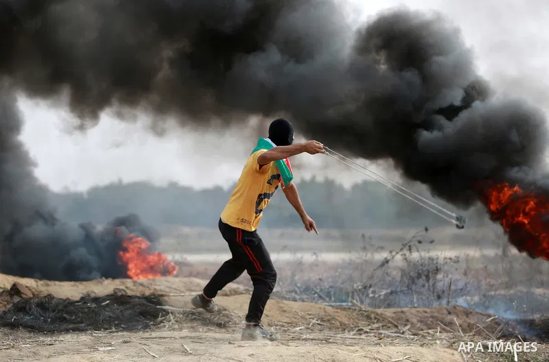 A Palestinian protester uses a sling shot to throw stones during clashes with Israeli security forces near the border between Israeli and central Gaza Strip, on October 23, 2015. Palestinian factions called for mass rall...