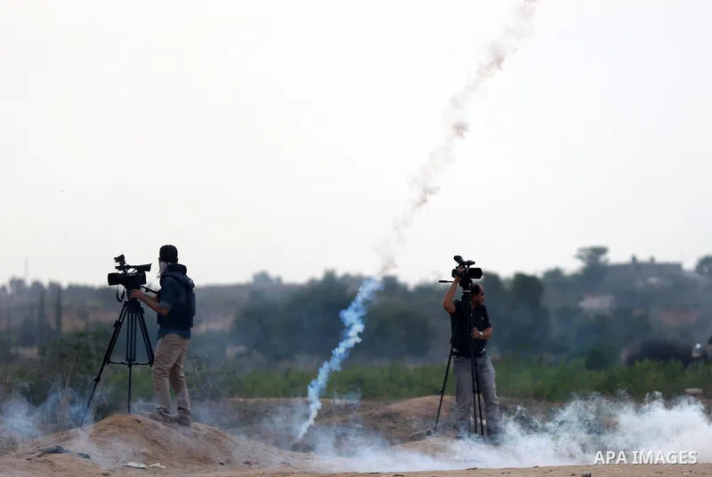 A Palestinian cameraman works amid tear gas fired by Israeli security forces during clashes with Palestinian protesters near the border between Israeli and central Gaza Strip, on October 23, 2015. Palestinian factions ca...