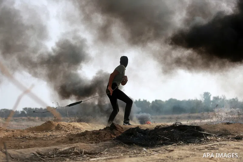 A Palestinian protester uses a sling shot to throw stones during clashes with Israeli security forces near the border between Israeli and central Gaza Strip, on October 23, 2015. Palestinian factions called for mass rall...