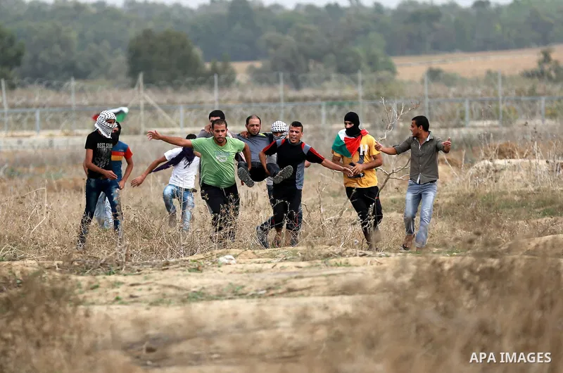 Palestinian protesters carry an injured comrade during clashes with Israeli security forces near the border between Israeli and central Gaza Strip, on October 23, 2015. Palestinian factions called for mass rallies agains...