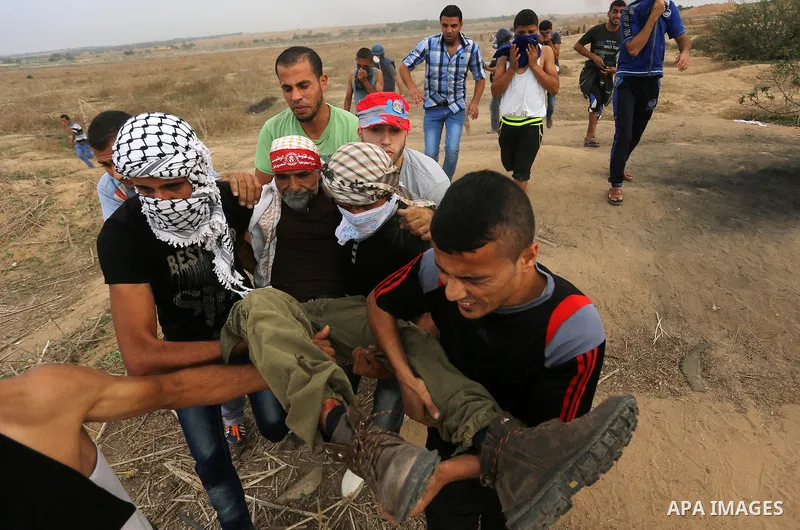 Palestinian protesters carry an injured comrade during clashes with Israeli security forces near the border between Israeli and central Gaza Strip, on October 23, 2015. Palestinian factions called for mass rallies agains...