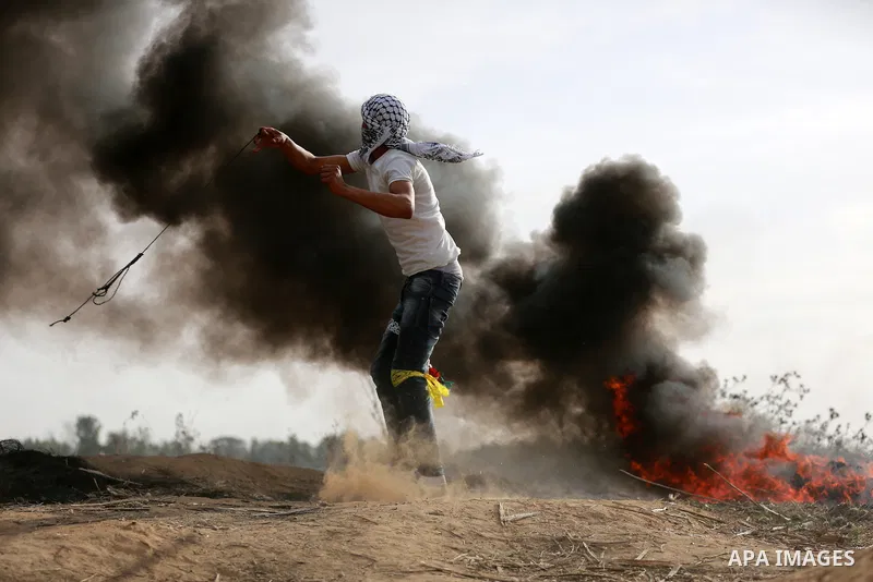A Palestinian protester uses a sling shot to throw stones during clashes with Israeli security forces near the border between Israeli and central Gaza Strip, on October 23, 2015. Palestinian factions called for mass rall...