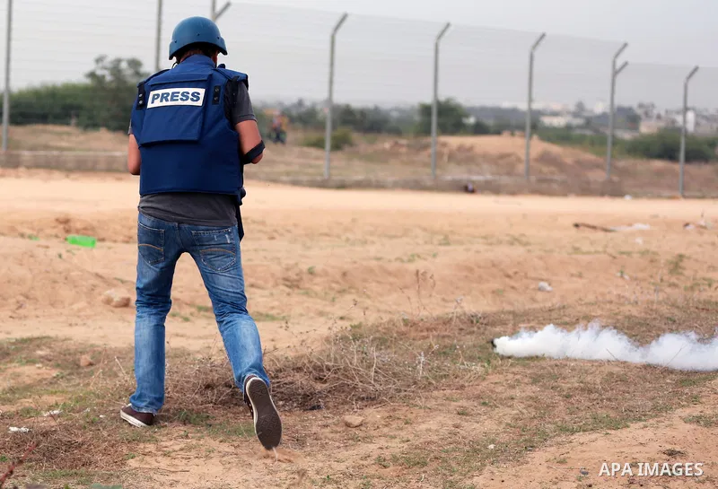 A Palestinian cameraman works amid tear gas fired by Israeli security forces during clashes with Palestinian protesters near the border between Israeli and central Gaza Strip, on October 23, 2015. Palestinian factions ca...