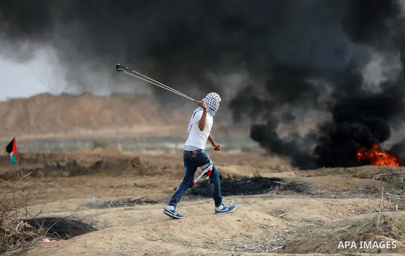 A Palestinian protester uses a sling shot to throw stones during clashes with Israeli security forces near the border between Israeli and central Gaza Strip, on October 23, 2015. Palestinian factions called for mass rall...