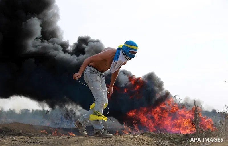 A Palestinian protester uses a sling shot to throw stones during clashes with Israeli security forces near the border between Israeli and central Gaza Strip, on October 23, 2015. Palestinian factions called for mass rall...