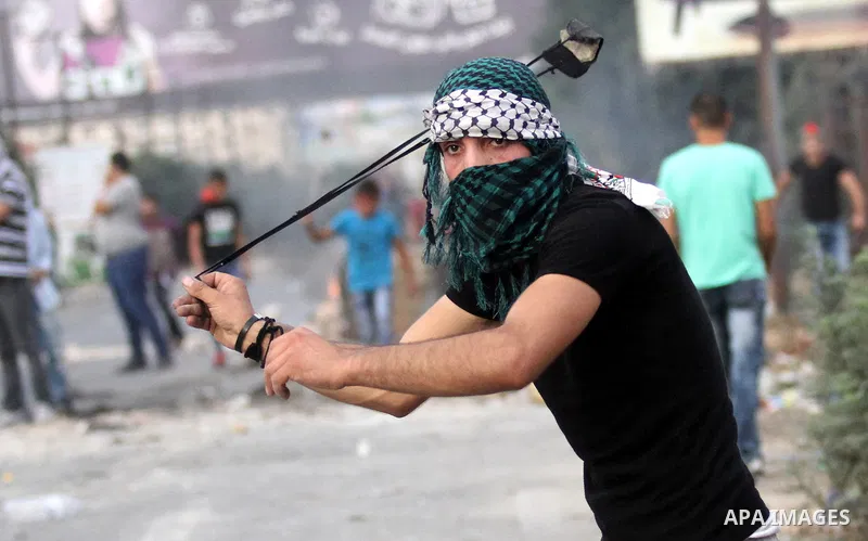 A Palestinian youth uses a sling shot to throw stones during clashes with Israeli security forces at the Hawara checkpoint, south of the West Bank city of Nablus on October 22, 2015. Palestinian factions called for mass...