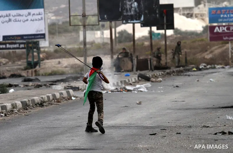 A Palestinian youth uses a sling shot to throw stones during clashes with Israeli security forces at the Hawara checkpoint, south of the West Bank city of Nablus on October 22, 2015. Palestinian factions called for mass...