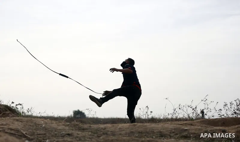A Palestinian protester uses a sling shot to throw stones during clashes with Israeli security forces near the border between Israeli and central Gaza Strip, on October 23, 2015. Palestinian factions called for mass rall...