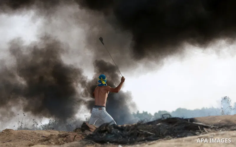 A Palestinian protester uses a sling shot to throw stones during clashes with Israeli security forces near the border between Israeli and central Gaza Strip, on October 23, 2015. Palestinian factions called for mass rall...