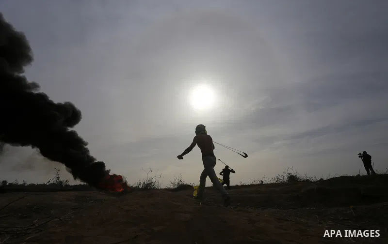 A Palestinian protester uses a sling shot to throw stones during clashes with Israeli security forces near the border between Israeli and central Gaza Strip, on October 23, 2015. Palestinian factions called for mass rall...