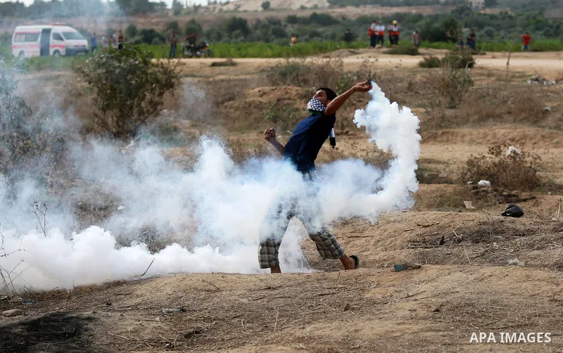 A Palestinian protester throws back a tear gas canister during clashes with Israeli security forces near the border between Israeli and central Gaza Stirp, on October 23, 2015. Palestinian factions called for mass rallie...