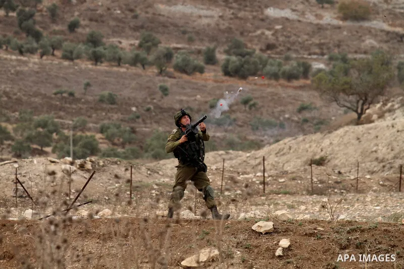 A member of Israeli security forces fires tear gas at Palestinian protesters during clashes at the Hawara checkpoint, south of the West Bank city of Nablus on October 22, 2015. Palestinian factions called for mass rallie...