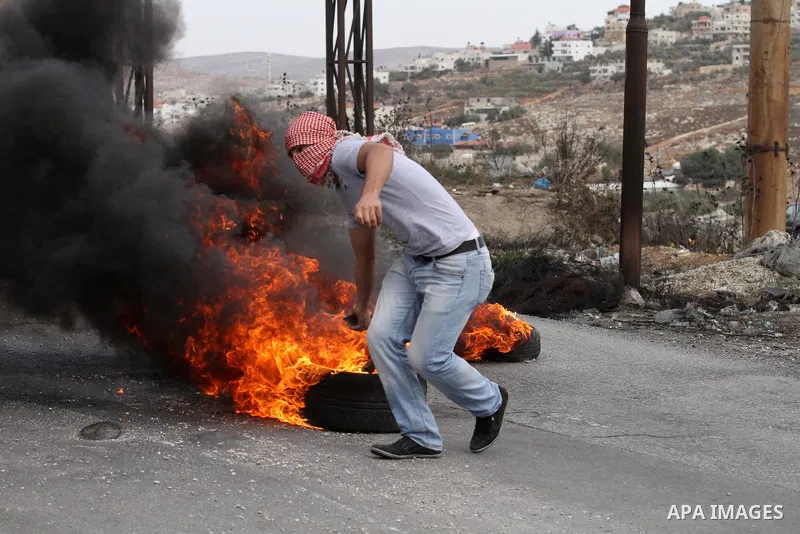 A Palestinian youth burns tires during clashes with Israeli security forces at the Hawara checkpoint, south of the West Bank city of Nablus on October 22, 2015. Palestinian factions called for mass rallies against Israel...