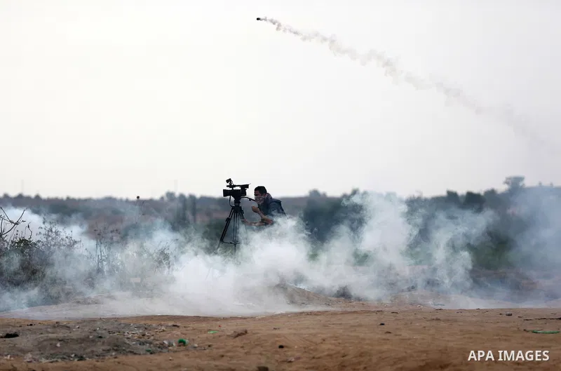 A Palestinian cameraman works amid tear gas fired by Israeli security forces during clashes with Palestinian protesters near the border between Israeli and central Gaza Strip, on October 23, 2015. Palestinian factions ca...