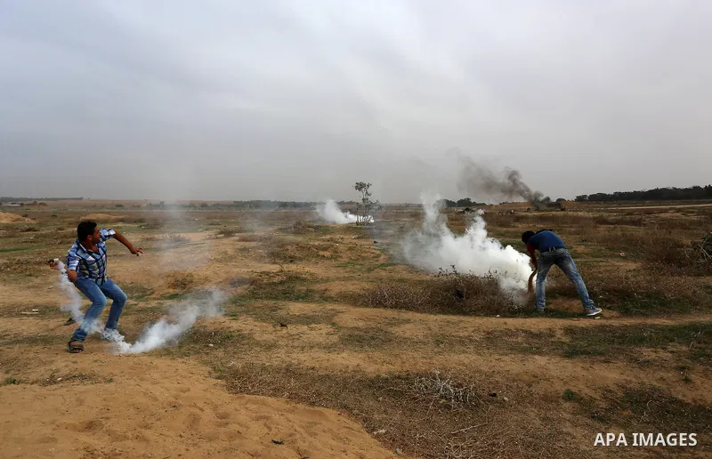A Palestinian protester throws back a tear gas canister during clashes with Israeli security forces near the border between Israeli and central Gaza Stirp, on October 23, 2015. Palestinian factions called for mass rallie...
