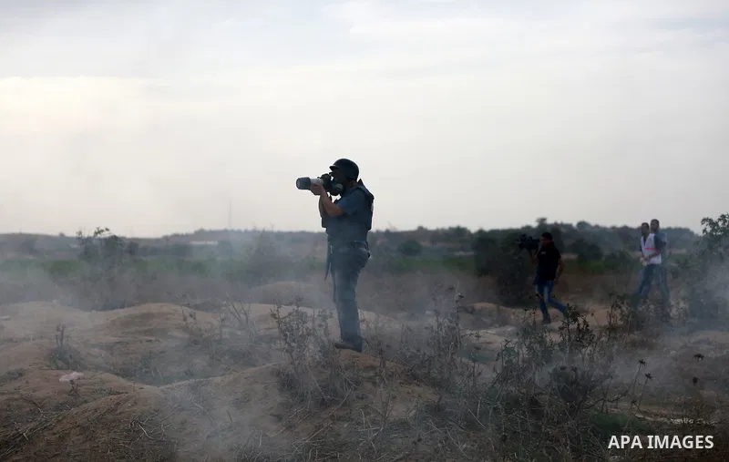 A Palestinian photographer works amid tear gas fired by Israeli security forces during clashes with Palestinian protesters near the border between Israeli and central Gaza Strip, on October 23, 2015. Palestinian factions...