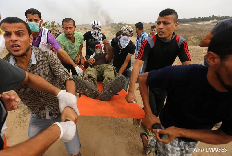 Palestinian protesters carry an injured comrade during clashes with Israeli security forces near the border between Israeli and central Gaza Strip, on October 23, 2015. Palestinian factions called for mass rallies agains...